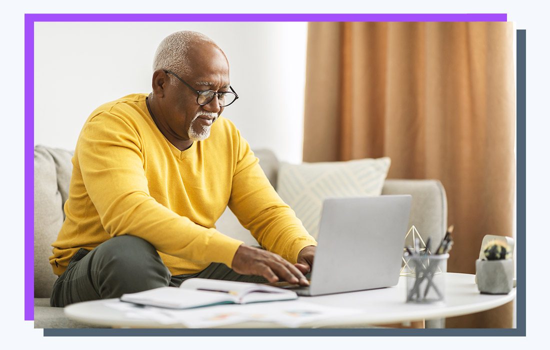 a man typing on a silver laptop.