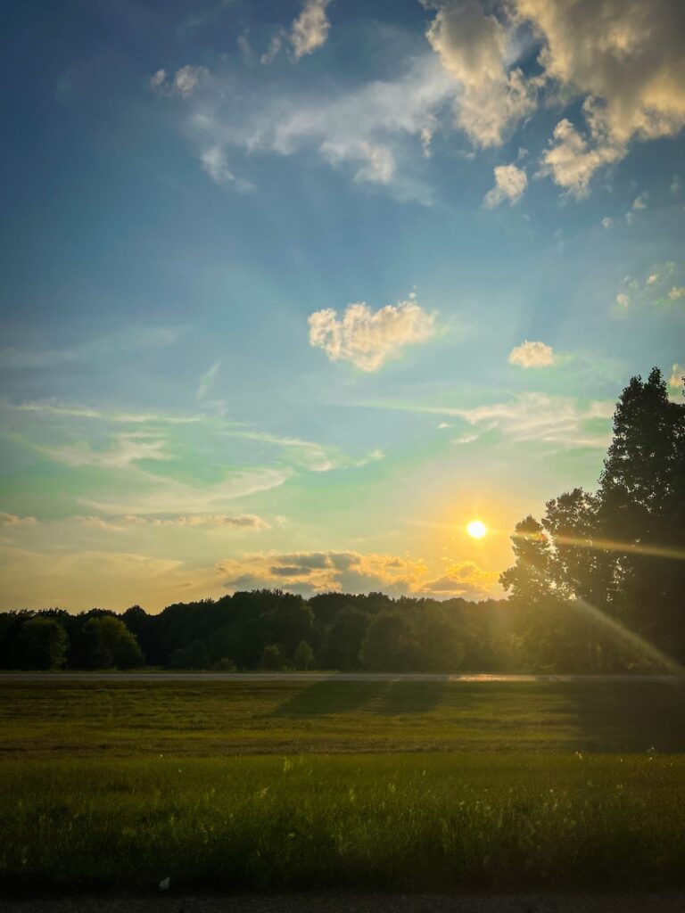 Sun is setting over a grassy field in Lansing, Michigan.