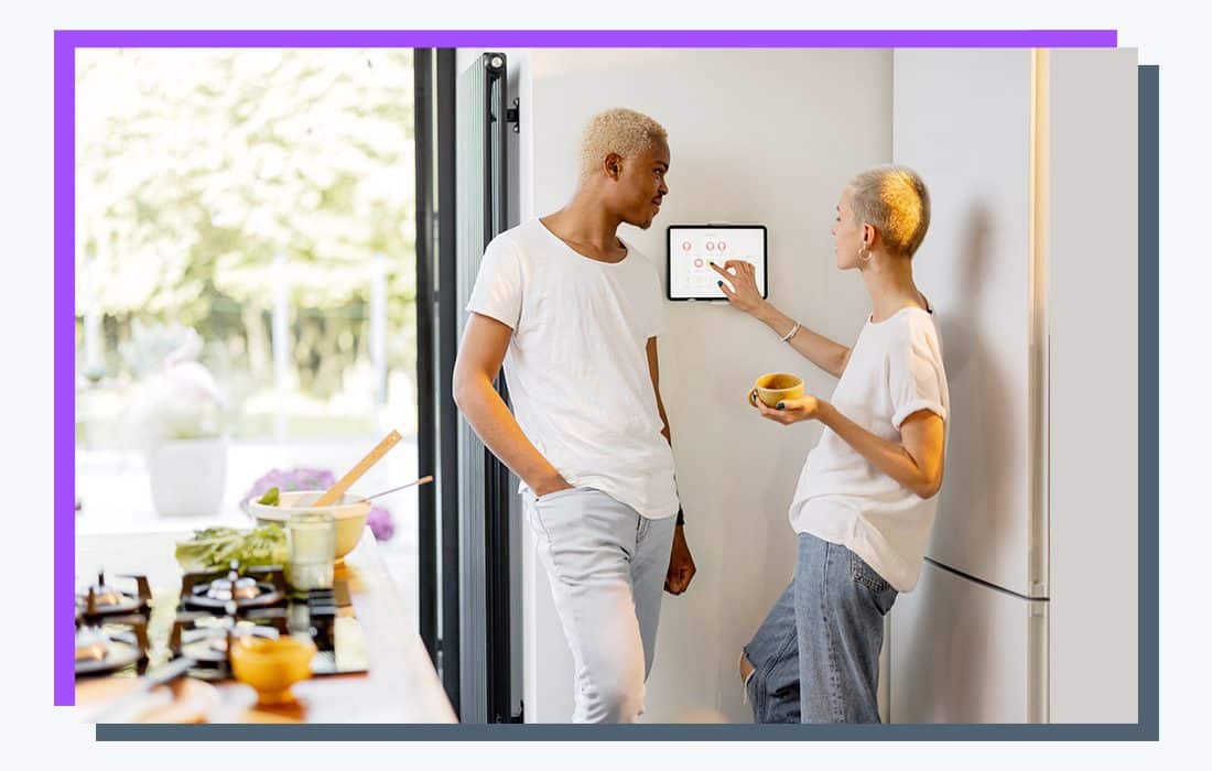 two people standing beside a smart home hub tablet.