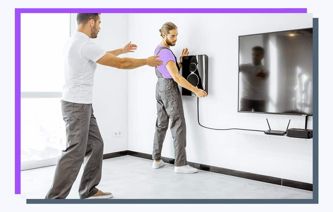 two workers mounting a TV speaker.