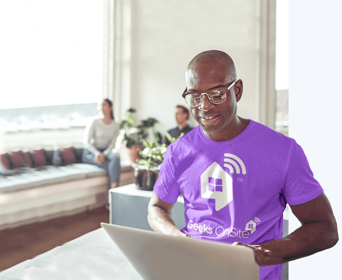 Geeks on Site employee in glasses and a purple t-shirt using a computer.