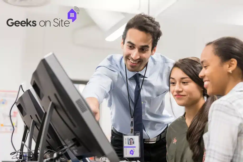 a man showing two people something on a desktop computer screen.